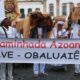 Fiéis de branco e com balaios de palha na cabeça atrás de uma faixa branca que diz "24ª caminhada azoany - salve obaluaiê"